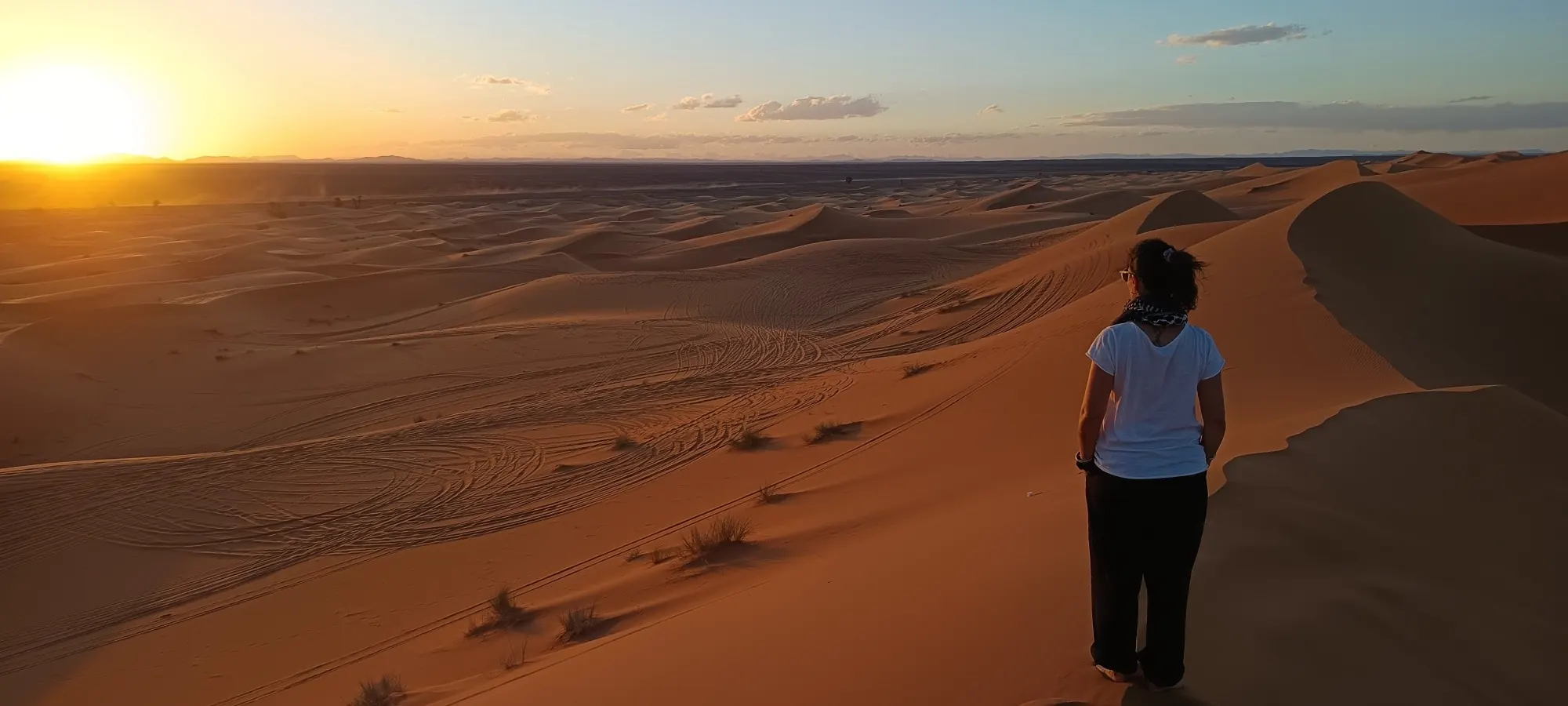 One of the tribe looking out over the desert dunes at sunset